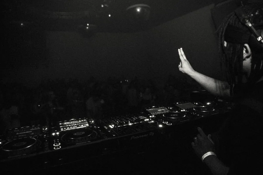 Black and white shot of Quentin Hiatus at the decks, hand raised