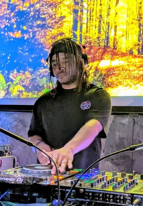 Quentin Hiatus DJing in front of an autumn forest video wall